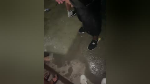 A video showing a person in black pants and a white shirt standing on a wet, muddy ground with debris scattered around, likely in a post-disaster or conflict zone.