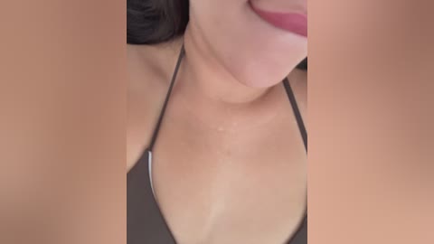 Video of a woman with fair skin, dark hair, and light pink lipstick, wearing a black string bikini, lying on her back, partially visible breasts.