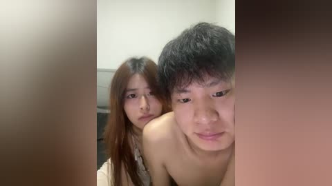Video of two young East Asian people, a man and a woman, topless in a bathroom, with blurred background and warm tones.