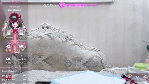 Video of a cartoon girl with pigtails, dressed in a pink dress, standing beside a white, ornate bed in a bedroom. The room features a chandelier and a pink pillow.