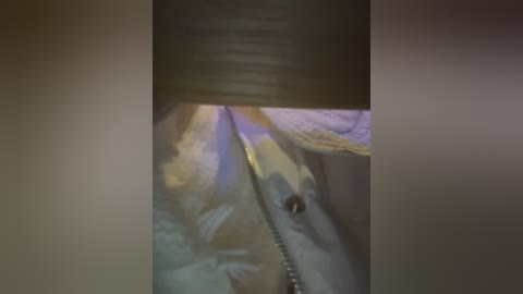 A close-up video of a person's face, partially obscured by a dark object, with blurred, soft lighting and indistinct background colors.