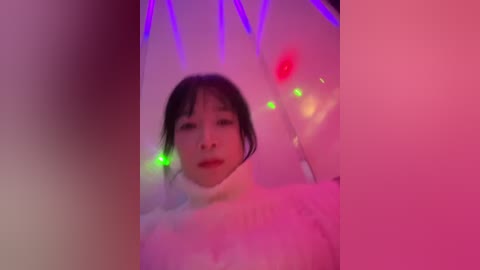 Video of a young Asian woman with straight black hair and fair skin, wearing a white turtleneck sweater, surrounded by purple and pink LED lights in a dimly lit room, creating a surreal, dream-like atmosphere.