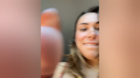 Blurry video of a young woman with light skin, brown hair, and a smile, partially obscured by a large, erect penis in the foreground.