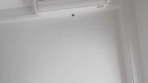 Video of a modern white interior wall with a recessed light fixture and an air conditioning unit mounted above it, creating a minimalist and clean aesthetic.