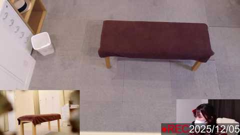 A video showing a beige-tiled room with a brown padded bench, a white trash can, and a person with dark hair and glasses sitting on the bench. A \"RECAP\" watermark is visible in the bottom right corner.