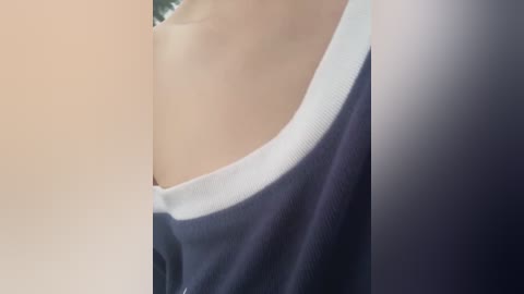 Video of a close-up of a person's upper body, showing a shoulder and part of a dark navy blue T-shirt with a white collar. The background is blurred, focusing on the fabric texture and color.