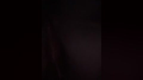This is a dimly lit video capturing a close-up of a person's face, with indistinct features and blurred background, suggesting a low-light setting or deliberate intentional blurriness.