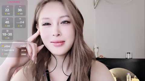 Video of a young Asian woman with light skin, long brown hair, wearing a black top, smiling, in a modern room with a digital calendar overlay.