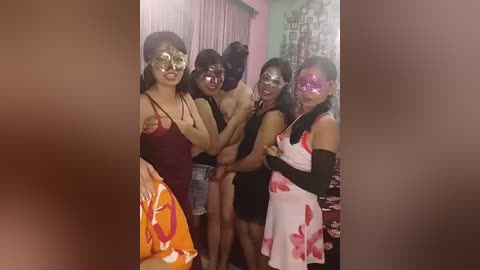 Video of five women in a dimly lit room, dressed in revealing, colorful costumes with masks, holding hands, smiling, and posing together.