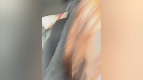 Video of a close-up, blurred, partially visible person with long, wavy hair, likely a woman, wearing a black jacket. The background is indistinct and out of focus, emphasizing the subject's hair and jacket.