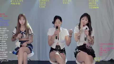 Video of three East Asian women, in school uniforms, seated on stools, singing into microphones, with a backdrop displaying Korean text and statistics.