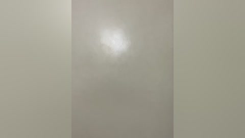 A video depicting a bare, smooth, off-white wall with a subtle, diffuse light source creating a slight gradient and reflection. The image lacks any objects, people, or textures, focusing solely on the minimalist, monochromatic wall.
