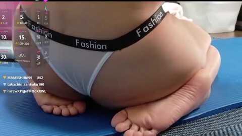 A video of a woman's bare backside in white underwear labeled \"Fashion\" while kneeling on a blue mat, with social media captions overlaid.