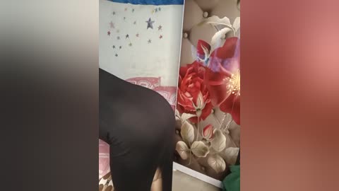 Media: Video of three partially blurred people: one in black, one in red, and one in beige, standing in front of a wall with a Cuban flag and a red floral arrangement.