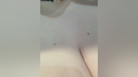 A close-up video of a pale-skinned, topless individual with small moles scattered across their chest. The image is blurred, making it difficult to discern specific details such as gender or facial features.