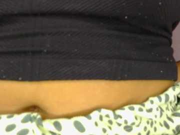 A video of a person's midsection, showcasing a black ribbed sweater pulled up, revealing light-skinned, bare lower abdomen. Below, a leopard-print fabric is visible. The image is close-up, focusing on the clothing and skin texture.