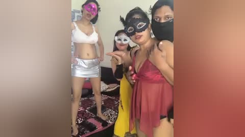 Media: Video of five women, two in white bras and metallic skirts, two in red lingerie, and one in a black mask, posing in a bedroom with a bed and colorful bedding.