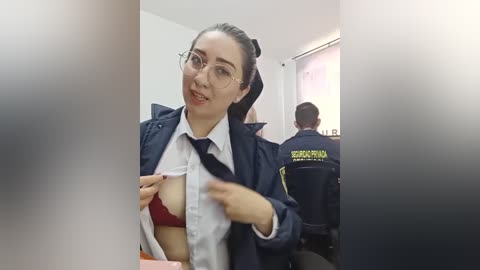 Video of a woman in a police uniform, exposing a red bra underneath, taken from an angle.