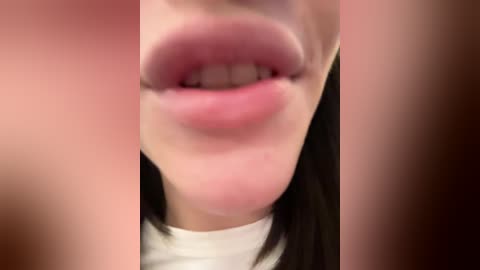 Video of a close-up of a person's mouth, showing slightly parted lips with visible teeth, fair skin, and a white shirt collar in the background.