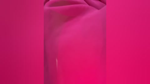 A video of a person's torso, obscured by a vibrant, pink, textured fabric that wraps around them, creating a sense of mystery and depth. The focus is on the fabric's folds and shadows, with no clear features of the person visible.