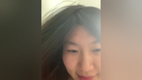 Video of a young Asian woman with long, dark hair, smiling, with a blurred background.