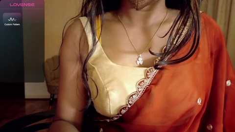 Video of a woman in an orange sari, showing a close-up of her medium-sized breasts in a yellow, lace-trimmed blouse.