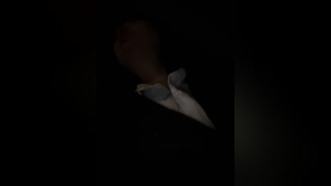 Video of a person's hand in a black jacket sleeve, with a white shirt cuff visible, against a dark, shadowy background, creating a mysterious, dramatic mood.
