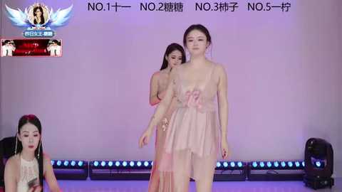 Video of a catwalk with two Asian women in light pink dresses, one adjusting the other's dress. Background has a purple wall with \"NO.1\" text and blue lights.