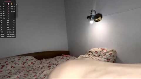 A video of a dimly lit bedroom with a single bed, a floral duvet, and a wall-mounted light fixture. A calendar with dates and events is visible on the left.
