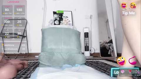 Video of a clean, modern bedroom with a white bed, a blue pillow, a white chair, a digital display, and a mirror reflecting a smiling face.