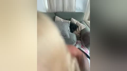 A video of a cozy living room with a beige couch, white curtains, and a person in a floral dress partially visible.