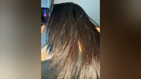 Video of a woman's long, straight, dark brown hair with subtle highlights, styled with a black hairdryer in a salon setting.