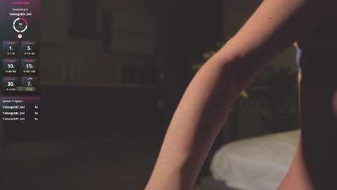 Media: A dimly lit video of a person's legs, possibly female, standing on a bed with a digital clock showing 10:15 on the left.