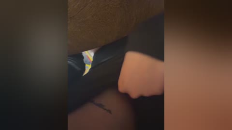 A close-up video of a hand holding a black notebook with a colorful pen, against a blurred background, highlighting the textured notebook cover and the subtle tattoo on the hand.