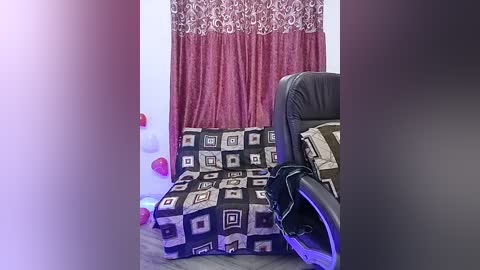 Video of a bedroom with a black leather couch, a red-patterned blanket, and a wall adorned with heart-shaped decorations.