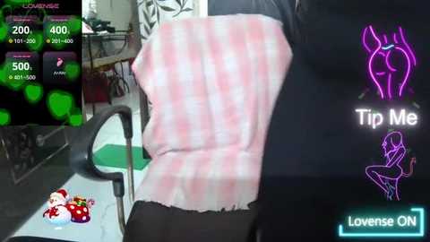 Video of a person with a pale pink, checkered body suit, wearing black shorts, standing in a dimly lit room with a green screen, a \"Tip Me\" sign, and a digital counter.