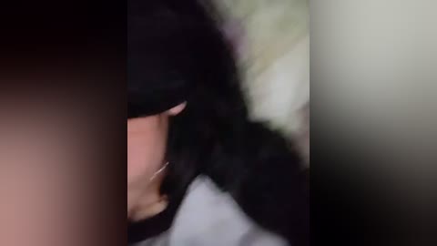 Video of a blurred, close-up of a person's face with dark hair, partially obscured by a vertical object, likely a pole or post, in a dimly lit, possibly outdoor setting.