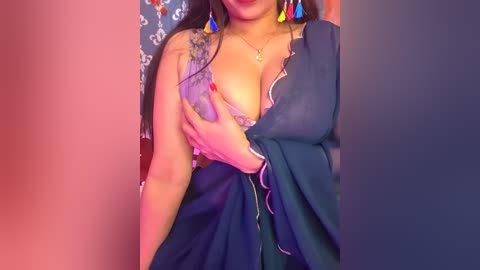 Video of a curvaceous woman with medium brown skin, wearing a purple lace bra, draped in a dark blue shawl, adorned with colorful earrings.