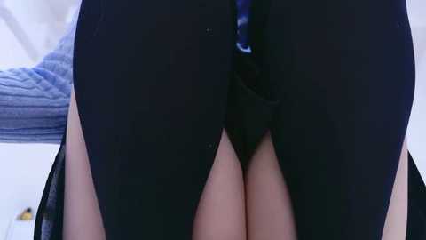 Video of a person's legs in black leather pants with a visible zipper, wearing a gray sweater, sitting on a white couch.