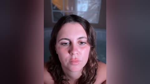 Video of a young woman with fair skin and wavy brown hair, making a pouty face, surrounded by blurred, darkened vertical bars, creating a dramatic, intense mood.