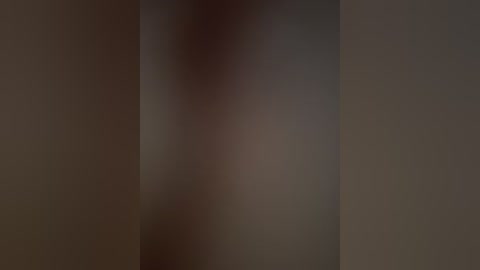 A blurred, monochrome video of a person's face, partially obscured by a dark vertical shadow, with indistinct features and a muted color palette.