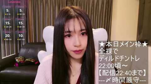 Media: Video of an Asian woman with long black hair, wearing a white blouse, sitting in a modern living room with gray curtains. Japanese text overlays the image, indicating a livestream.