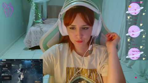 Video of a young woman with red hair, wearing headphones, seated in a pastel green gaming chair, looking at a computer screen displaying a game.