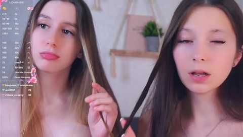 Video of a young Asian woman with long black hair, fair skin, and slender physique, smiling and winking, indoors with a pink plant on a shelf.