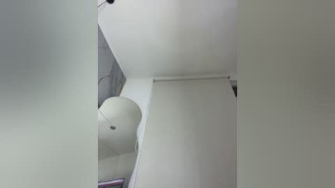 A video showing a minimalist interior ceiling with a large, white, spherical light fixture hanging centrally. The room's walls are painted in a light, neutral color, creating a serene, modern atmosphere.
