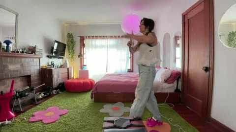 A video of a woman dancing in a colorful, cluttered bedroom with a pink bed, green carpet, and floral rug.