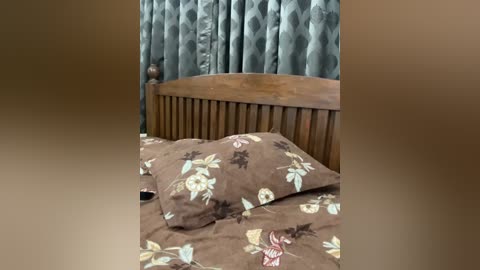 A video of a cozy bedroom with a wooden bedhead, brown floral-patterned bedspread, and blue diamond-patterned curtains.