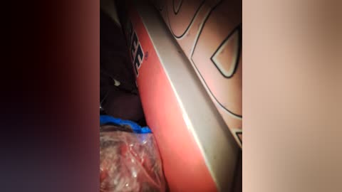 Video of a partially opened, red and white can of Spam with a plastic bag of raw meat inside, set against a dark, blurry background.