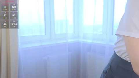 A video of a person in a white shirt and blue pants standing near a window with sheer white curtains, displaying a weather app with temperature, humidity, and wind speed.
