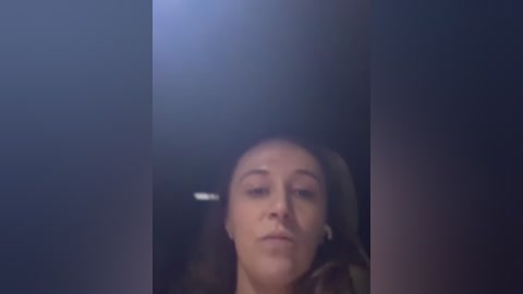 Video of a woman with medium skin tone and brown hair, eyes closed, leaning against a dark, blurred background. She appears to be in a contemplative or relaxed state.